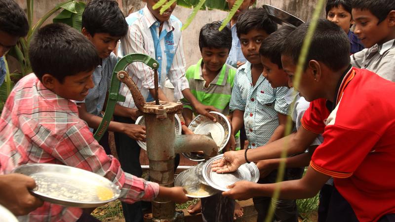 Young group cleaning plates in India